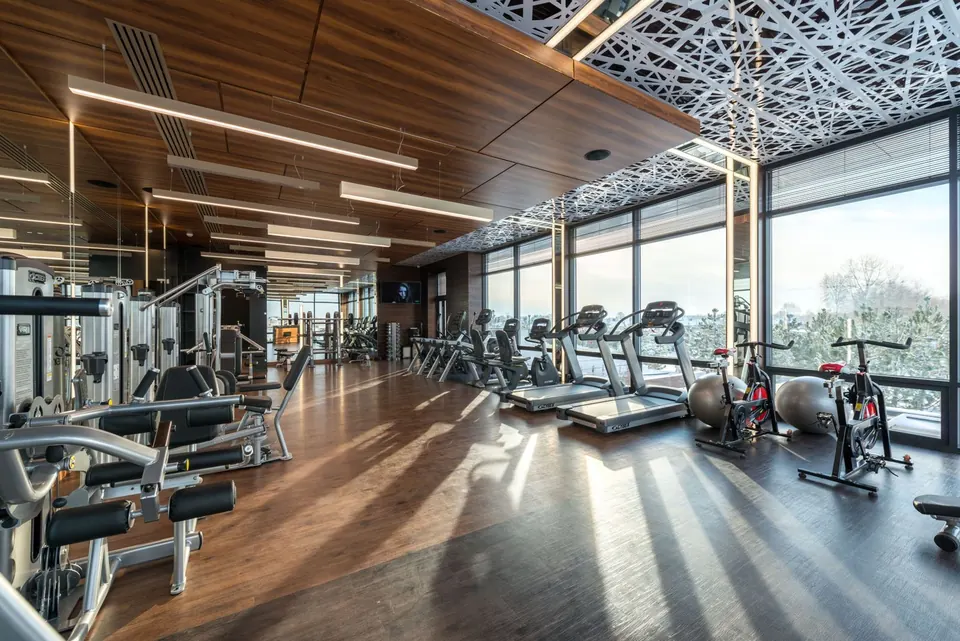 Gimnasio amplio con caminadoras junto a los ventanales